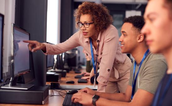 adult woman helping male student on computer