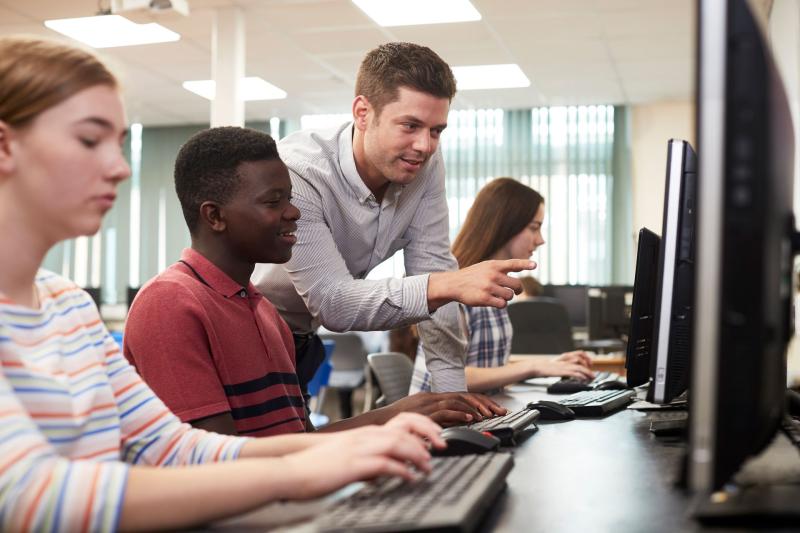 adult male helps students on computers
