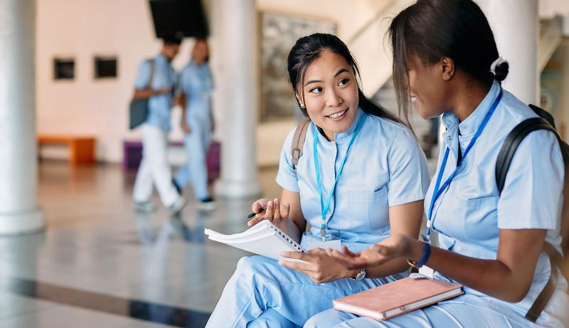 Two nursing students talking in a hallway.
